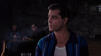 Movie still from “Goodfellas” (1990), directed by Martin Scorsese – A man sitting in front of a glass of water; Medium shot, Over the shoulder angle