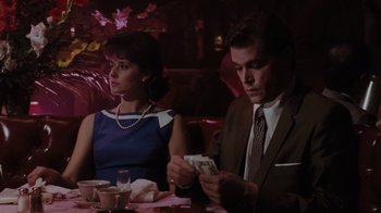 Movie still from “Goodfellas” (1990), directed by Martin Scorsese – A man and a woman sitting at a dinner table holding money; Medium shot, Over the shoulder angle