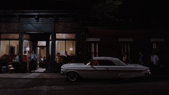 Movie still from “Goodfellas” (1990), directed by Martin Scorsese – An old car parked on the side of the street; Extreme Wide shot, Over the shoulder angle