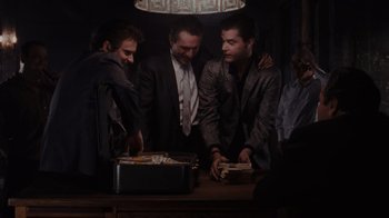 Movie still from “Goodfellas” (1990), directed by Martin Scorsese – A group of men standing around a table; Wide shot, High angle