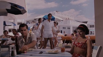 Movie still from “Goodfellas” (1990), directed by Martin Scorsese – A group of people sitting at a table with food; Wide shot, Over the shoulder angle