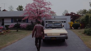 Movie still from “Goodfellas” (1990), directed by Martin Scorsese – A man walking down the street in front of an old car; Wide shot, Low angle