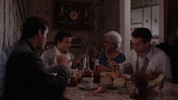 Movie still from “Goodfellas” (1990), directed by Martin Scorsese – A group of people sitting around a table eating food; Medium shot, High angle