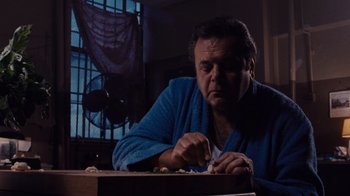 Movie still from “Goodfellas” (1990), directed by Martin Scorsese – A man sitting at a table in front of a window; Close Up shot, Low angle