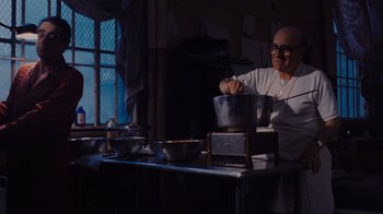 Movie still from “Goodfellas” (1990), directed by Martin Scorsese – A man in a white shirt is making food in a kitchen; Medium shot, Low angle
