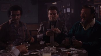 Movie still from “Goodfellas” (1990), directed by Martin Scorsese – A man sitting at a table with a tie in front of him; Medium shot, Over the shoulder angle