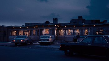Movie still from “Goodfellas” (1990), directed by Martin Scorsese – Cars are parked in a parking lot near a restaurant; Extreme Wide shot, High angle