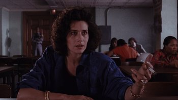Movie still from “Goodfellas” (1990), directed by Martin Scorsese – A woman sitting at a table in front of a group of people; Close Up shot, Over the shoulder angle