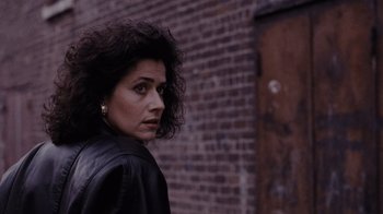 Movie still from “Goodfellas” (1990), directed by Martin Scorsese – A woman in a black jacket standing in front of a brick wall; Close Up shot, Over the shoulder angle