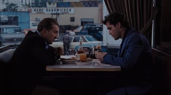 Movie still from “Goodfellas” (1990), directed by Martin Scorsese – Two men are sitting at a table in a restaurant; Medium shot, Over the shoulder angle