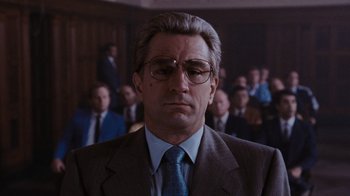 Movie still from “Goodfellas” (1990), directed by Martin Scorsese – A man in a suit and tie in front of a group of people; Close Up shot, Low angle