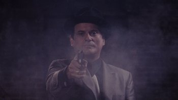 Movie still from “Goodfellas” (1990), directed by Martin Scorsese – A man in a suit and hat holding a gun; Medium shot, Low angle