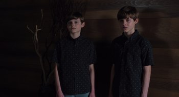 Movie still from “Goodnight Mommy” (2022), directed by Matt Sobel – Two young boys standing next to each other in front of a wall; Medium shot, High angle