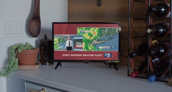 Movie still from “Goodnight Mommy” (2022), directed by Matt Sobel – A television screen showing a weather alert; Extreme Close Up shot, Over the shoulder angle