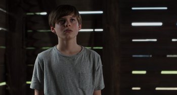 Movie still from “Goodnight Mommy” (2022), directed by Matt Sobel – A boy in a gray shirt is looking at the camera; Medium shot, Low angle