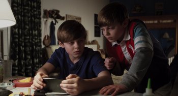 Movie still from “Goodnight Mommy” (2022), directed by Matt Sobel – Two young boys looking at a tablet computer; Medium shot, High angle
