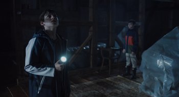 Movie still from “Goodnight Mommy” (2022), directed by Matt Sobel – A boy holding a flashlight while standing next to another boy; Medium shot, Low angle