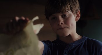 Movie still from “Goodnight Mommy” (2022), directed by Matt Sobel – A young boy is holding a piece of paper; Close Up shot, Low angle