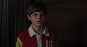 Movie still from “Goodnight Mommy” (2022), directed by Matt Sobel – A young boy in a red and yellow shirt; Close Up shot, Over the shoulder angle