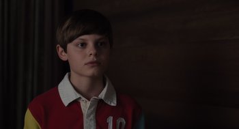 Movie still from “Goodnight Mommy” (2022), directed by Matt Sobel – A boy in a red and white shirt is looking to his left; Close Up shot, Over the shoulder angle