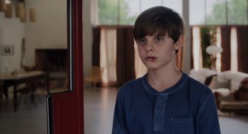 Movie still from “Goodnight Mommy” (2022), directed by Matt Sobel – A young boy standing in front of an open door; Close Up shot, Over the shoulder angle