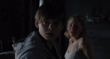 Movie still from “Goodnight Mommy” (2022), directed by Matt Sobel – A boy and a woman in a dark room; Close Up shot, Over the shoulder angle