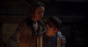 Movie still from “Goodnight Mommy” (2022), directed by Matt Sobel – A woman and a young boy standing next to each other; Medium shot, Over the shoulder angle