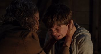 Movie still from “Goodnight Mommy” (2022), directed by Matt Sobel – A young boy is crying as a young woman looks on; Close Up shot, Over the shoulder angle