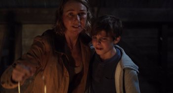 Movie still from “Goodnight Mommy” (2022), directed by Matt Sobel – A woman and a boy standing next to each other; Medium shot, Over the shoulder angle