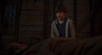 Movie still from “Goodnight Mommy” (2022), directed by Matt Sobel – A young boy standing in front of a wooden wall; Medium shot, High angle