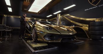 Movie still from “Gran Turismo” (2023), directed by Neill Blomkamp – A man standing in front of a gold plated car; Extreme Wide shot, Low angle