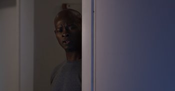 Movie still from “Gran Turismo” (2023), directed by Neill Blomkamp – A man standing next to a white wall; Close Up shot, Low angle