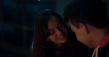 Movie still from “Gran Turismo” (2023), directed by Neill Blomkamp – A young woman smiles at a young man; Close Up shot, Over the shoulder angle