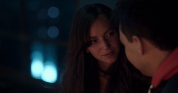 Movie still from “Gran Turismo” (2023), directed by Neill Blomkamp – A young woman looking at a young man in a dark room; Close Up shot, Over the shoulder angle