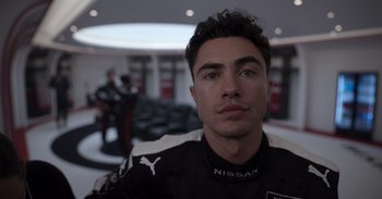 Movie still from “Gran Turismo” (2023), directed by Neill Blomkamp – A person wearing a racing suit; Close Up shot, Low angle