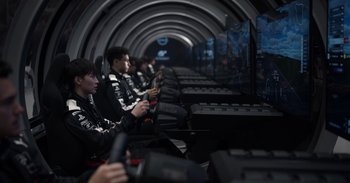 Movie still from “Gran Turismo” (2023), directed by Neill Blomkamp – A group of people playing a video game in a tunnel; Wide shot, High angle
