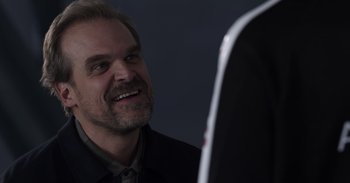 Movie still from “Gran Turismo” (2023), directed by Neill Blomkamp – A person wearing a suit and tie; Close Up shot, Over the shoulder angle