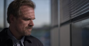 Movie still from “Gran Turismo” (2023), directed by Neill Blomkamp – A person wearing a suit and tie; Close Up shot, Low angle