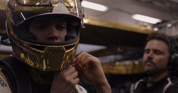 Movie still from “Gran Turismo” (2023), directed by Neill Blomkamp – A man putting on a gold helmet in a garage; Close Up shot, Low angle