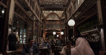 Movie still from “Gran Turismo” (2023), directed by Neill Blomkamp – A group of people sitting at tables in a building; Extreme Wide shot, Over the shoulder angle