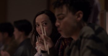 Movie still from “Gran Turismo” (2023), directed by Neill Blomkamp – A woman and a man are holding chopsticks in their hands; Close Up shot, Over the shoulder angle