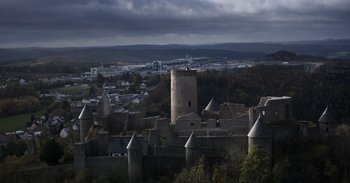 Movie still from “Gran Turismo” (2023), directed by Neill Blomkamp – An aerial view of a city with a castle like structure; Extreme Wide shot, High angle