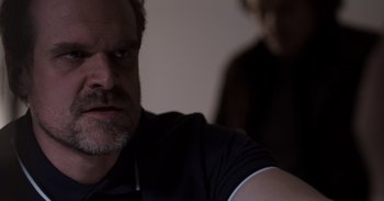 Movie still from “Gran Turismo” (2023), directed by Neill Blomkamp – A person sitting in front of a wall; Close Up shot, Over the shoulder angle