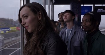 Movie still from “Gran Turismo” (2023), directed by Neill Blomkamp – A group of people standing next to each other in a room; Close Up shot, Over the shoulder angle