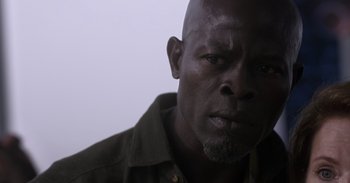 Movie still from “Gran Turismo” (2023), directed by Neill Blomkamp – A man's face in a dark room; Close Up shot, Low angle