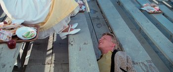 Movie still from “Grease” (1978), directed by Randal Kleiser – A man laying on the ground next to a woman's shoes; Medium shot, High angle