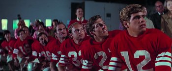Movie still from “Grease” (1978), directed by Randal Kleiser – A group of football players lined up in a row; Medium shot, Low angle