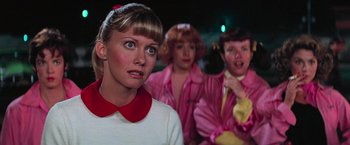 Movie still from “Grease” (1978), directed by Randal Kleiser – A group of young people dressed up like grease; Close Up shot, Over the shoulder angle