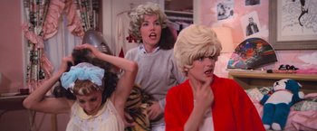 Movie still from “Grease” (1978), directed by Randal Kleiser – A group of people in wigs and hair curlers; Medium shot, Low angle