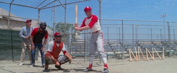 Movie still from “Grease” (1978), directed by Randal Kleiser – A baseball player holding a baseball bat on top of a baseball field; Wide shot, Low angle